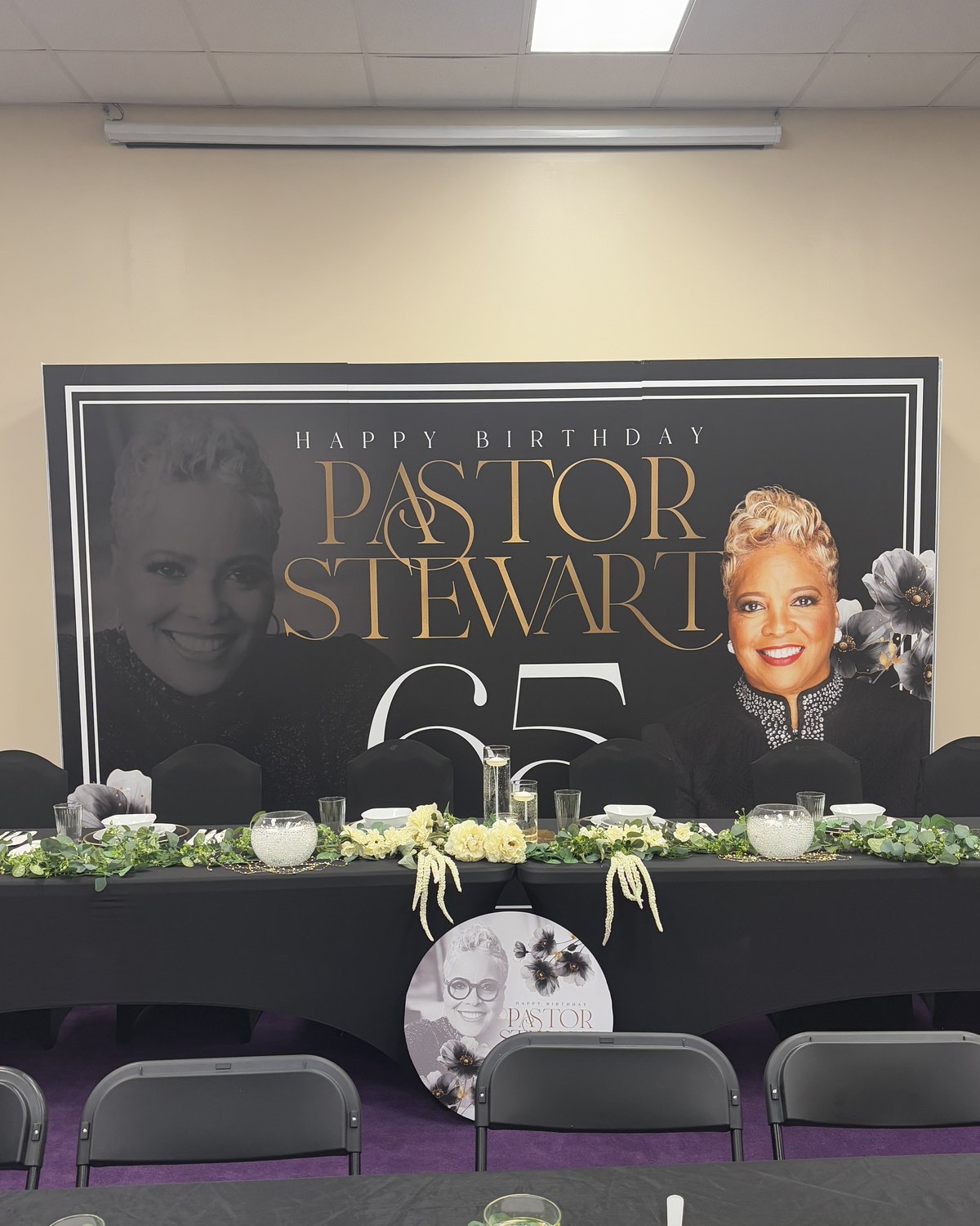 A Happy Birthday Pastor Stewart 65 backdrop behind the head table at a church celebration